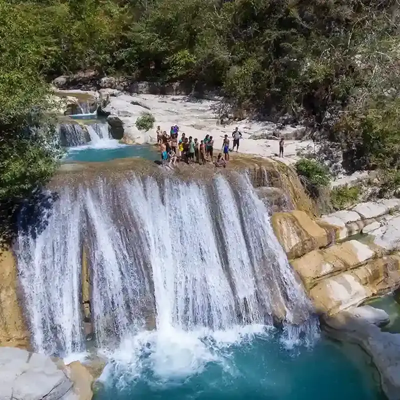 Tanggedu Waterfall pouring over white rock into blue pools