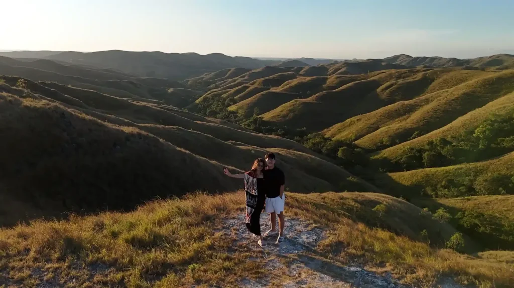 Couple on the ridge of Bukit Wairinding in East Sumba at golden hour