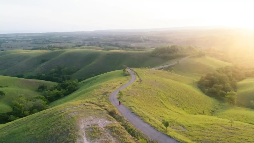 Road winding through the green slopes of Tanarara Hill in East Sumba