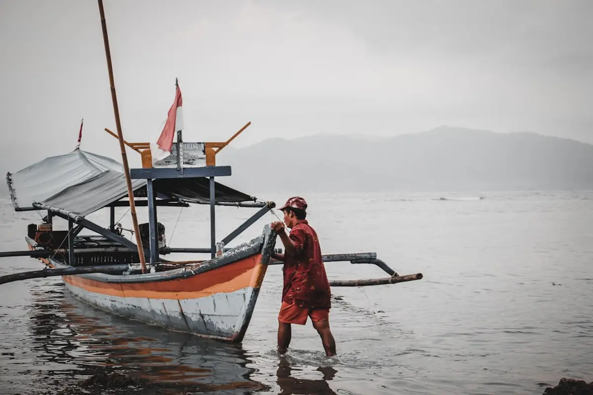 A traditional wooden phinisi charter boat anchored off the Sumba coast